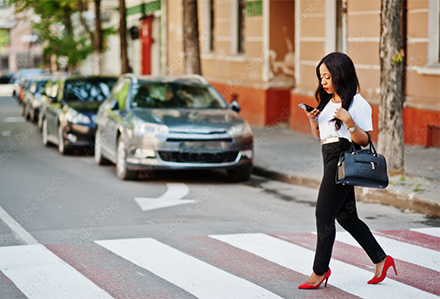 Woman crossing street while reading her phone